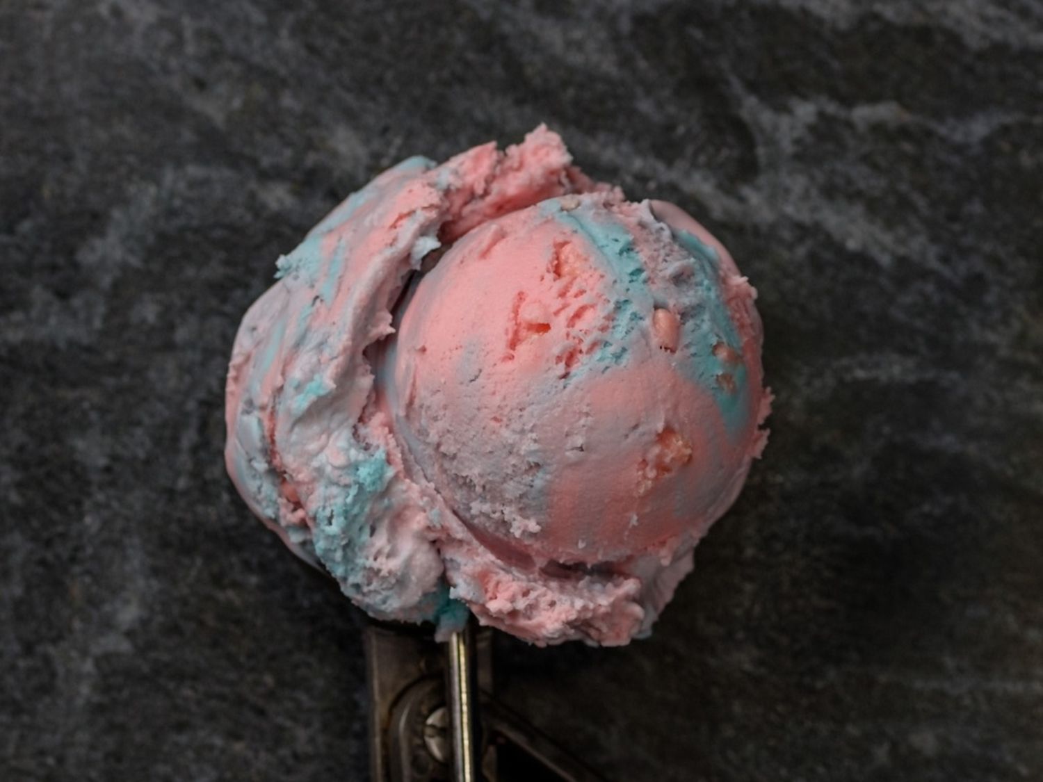 A fresh scoop of cotton candy ice cream in a metal scooper